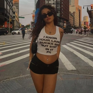 Close-up of white cropped tank top with black text print worn in urban street setting