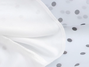 Nahaufnahme von weißem Strickgewebe und grauem Polka-Dot-Muster auf weichem Stoff