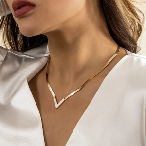Detail of a gold V-shaped pendant necklace with white inlay on a flat snake chain