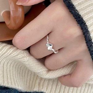 Close-up of a 925 sterling silver heart ring with twisted band on a model's finger
