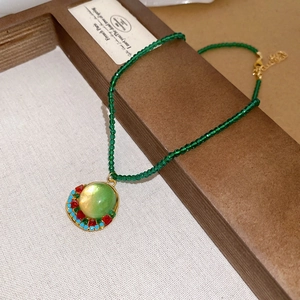 Detail of vintage round green resin pendant necklace with crystal beaded chain and gold inlay