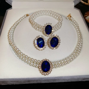 Detail of oval blue sapphire pendant and pearl jewelry set in white velvet gift box