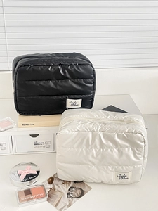 Detailed view of quilted waterproof nylon cosmetic bags in black and cream white colors