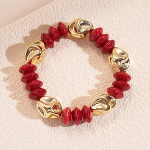 Detailed macro of gold-tone irregular beads and red marbled acrylic beaded bracelet