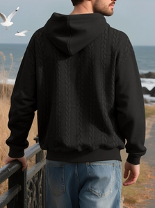 Back view of a black men's hooded knit sweater with textured jacquard on a beach