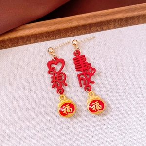 Detail view of New Year earrings with red Chinese characters and golden lucky bag charms