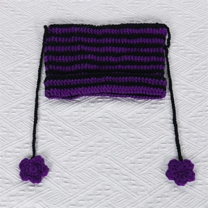 Detailed view of handmade purple and black striped knit cat ear hat with floral tassels