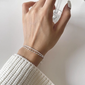 Close-up of a layered S925 sterling silver chain bracelet with beads on a wrist