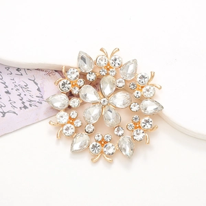 Elegant gold crystal flower brooch with shimmering clear rhinestones on white surface