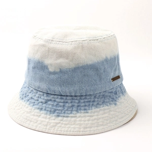 Détail d'un chapeau bob en jean dégradé montrant la texture et la plaque en métal