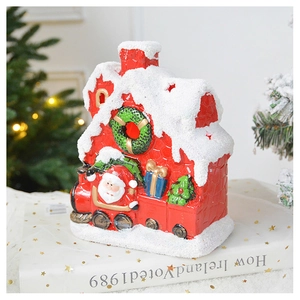 Close-up of a red ceramic Christmas house with snowy roof and Santa's train detail