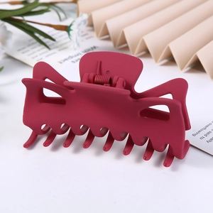 Close-up of a large wine red matte hair claw clip with a hollow geometric design