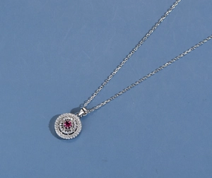 Macro detail of silver pendant with red round gemstone and hollow pave diamond setting
