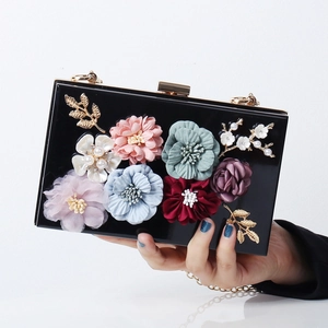Elegant black acrylic clutch with 3D fabric flowers and gold leaf details for evening events