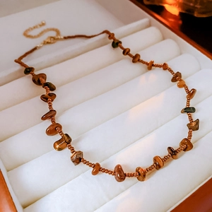 Detailed macro view of vintage tiger eye stone beaded necklace on a white velvet tray