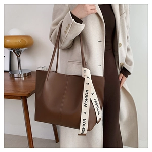 Detail of a dark brown large tote bag with a fashion canvas ribbon in a cozy home setting