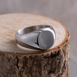 Close-up of a minimalist silver round signet ring on a rustic wood tree stump background