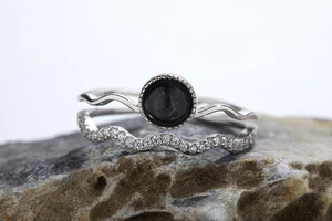 Macro shot of S925 silver ring set with black gemstone and wavy band on stone