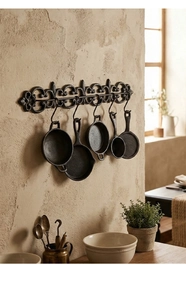 Détail de décoration murale en fonte avec fleur de lys et cinq mini poêles rétro