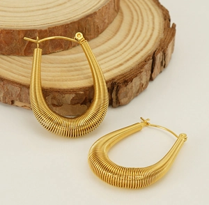 Detail of gold U-shaped spring earrings with spiral metal wire texture and clasp closure