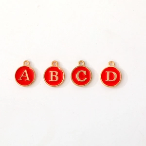 Macro detail of red enamel round gold charms with letters A B C and D for jewelry