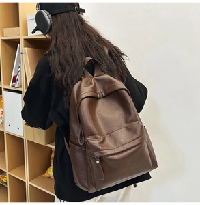 Deep brown PU leather backpack shown on a model with a spacious main pocket and minimalist design