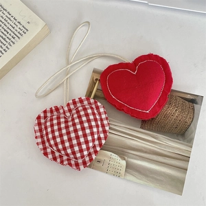 Detail van rode en geruite stoffen hartvormige hangers met witte stiksels en ophangkoord