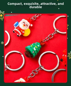 Close-up of Santa Claus and Christmas tree PVC keychains on a festive red background