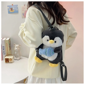 Detail of cute penguin plush backpack with blue fish accessory on model's back
