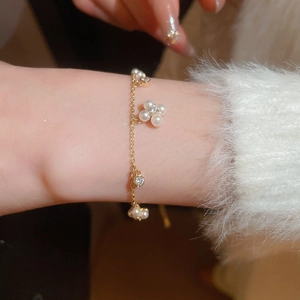 Detailed view of a gold pearl flower bracelet featuring rhinestones on a soft fabric