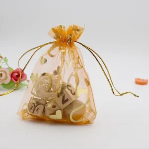 Close-up of orange organza gift bag with gold heart patterns and drawstring closure