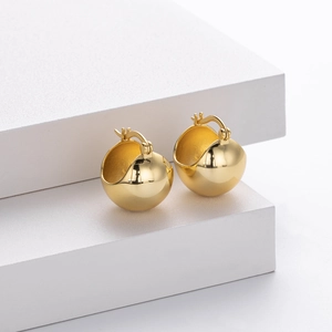 Detailed view of polished gold dome earrings on white geometric minimalist display