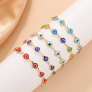 Kleurrijke Evil Eye armband met gouden ketting op witte standaard en perzik achtergrond