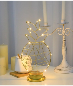 Close-up of golden pineapple LED night light with warm yellow glow on metal base