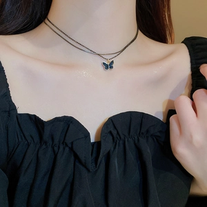 Close-up of double layer choker with blue butterfly pendant on a gold chain