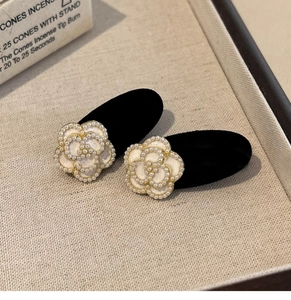 Detailed close-up of velvet camellia hair clips with white pearls and gold edges