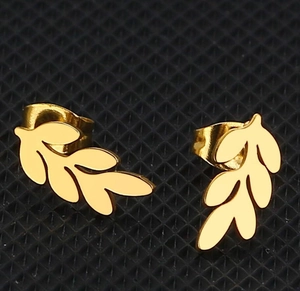 Macro shot of gold leaf stud earrings with detailed vein patterns on black background