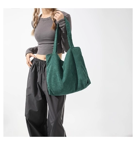 Detail view of large dark green corduroy tote bag showing ribbed texture and wide strap