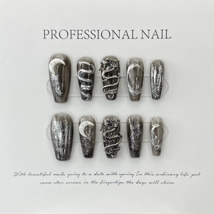 Detail of grey cat-eye press-on nails featuring 3D silver dragon charms and glitter