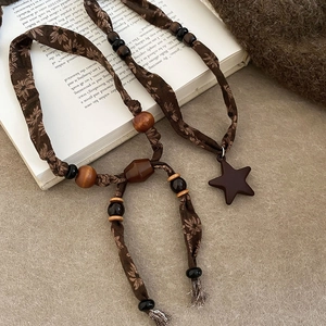 Détail du collier rétro en lin avec perles en bois et pendentif étoile sur un livre