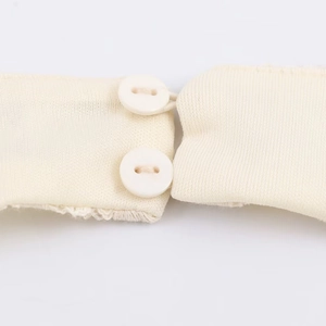 Detailopname van een beige kanten jurk met tweeknoopssluiting en een gebreide textuur op de rug
