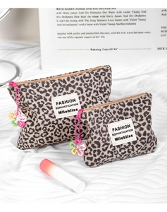 Dettaglio dei beauty case leopardati con ciondoli a fiore ed etichette del brand