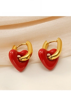 Detailed close-up of vintage red enamel heart charms on gold hoop earrings over silk fabric