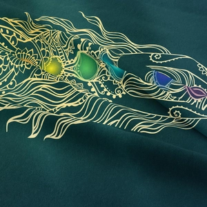 Macro detail of soft fabric with gold feather pattern and colorful gemstone prints