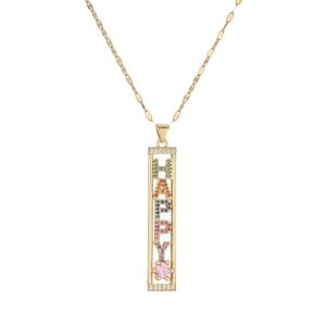 Close-up of golden necklace with colorful crystal HAPPY pendant and pink gemstone