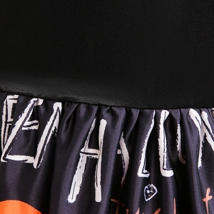Detailed close-up of girls Halloween dress featuring black bodice and printed pleated skirt