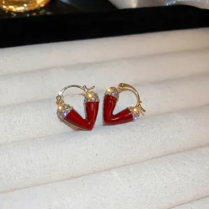 Elegant red heart earrings with white crystals and gold finish in a jewelry box