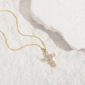 Detail of gold cross pendant with marquise and round cubic zirconia on stone base