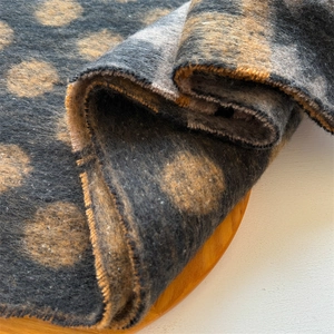 Macro shot of dark grey scarf fabric showing golden polka dots and soft texture