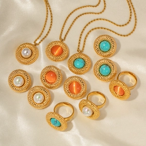 Detail of 18k gold heart and circle jewelry set with pearls and stones on silk fabric